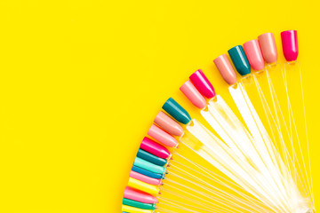 work desk at nail bar with palette of nail polish for manicure on yellow background top view mockup