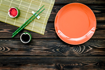 oriental table set up with plate and bamboo sticks for sushi and maki on wooden background top view space for text