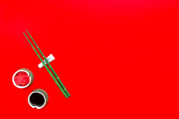 asian cuisine set with bamboo sticks, soy sauce and ginger for sushi and maki on red background top view mock up