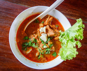 Curry soup pork bone with coconut milk and herbal spices spicy in bowl on wooden background