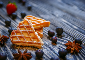Waffles hearts with blueberry and strawberry tied with a string on the dark wooden background.