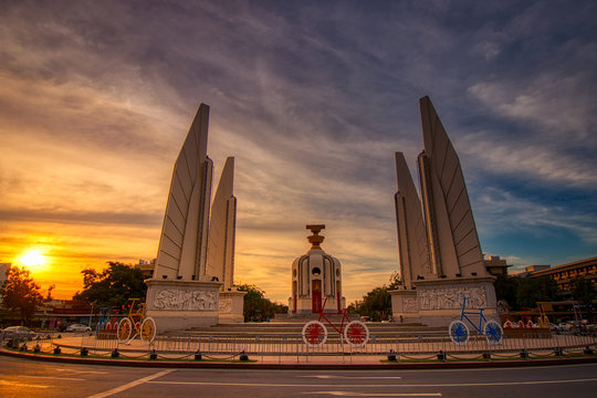 view of the democracy monument in Bangkok with the sundown and yellow lights in the background 