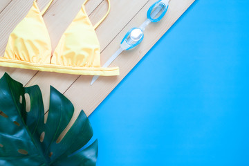 Creative flat lay of summer holiday concept with bikini on wooden and blue colour background.