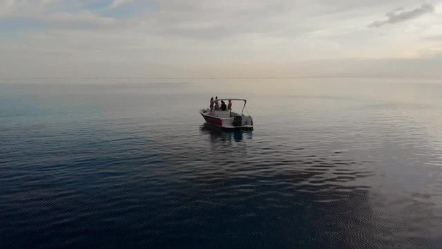 Aerial Pan Right: Boat Floating In Empty Blue Ocean Surrounded By Mountains in Bora Bora, French Polynesia