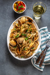 Seafood Pasta. ITALIAN SPAGHETTI ALLE VONGOLE. Clams spaghetti on white plate with white wine, gray background. Top view