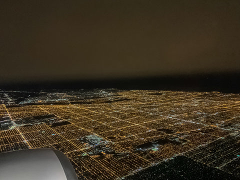 View of Chicago's illuminated city night lights seen through the window of an airplane