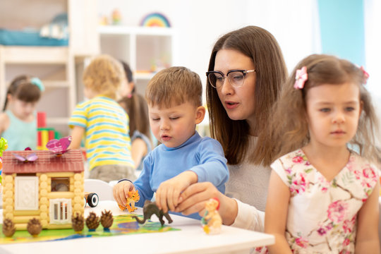 Group of kids playing with teacher in kindergarten