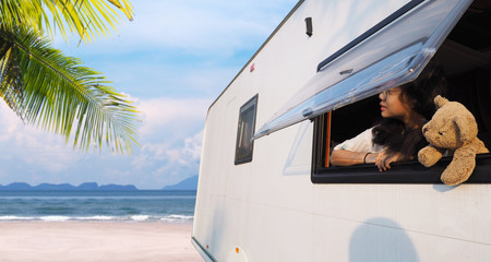 girl looking out of camper van window on summer beach