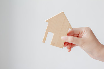 Fototapeta na wymiar Young woman hand holding miniature wood house or model of home,Choosing the right real estate property, or new home in a housing development or community.