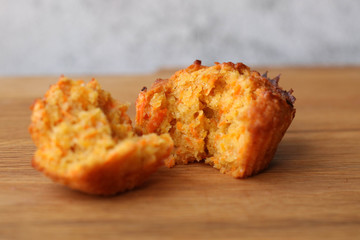 A piece of broken homemade delicious carrot muffin on table, selective focus, side view