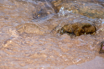 Klares Wasser fließt am Strand über Steine und Felsen