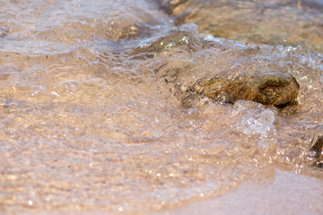 Klares Wasser fließt am Strand über Steine und Felsen