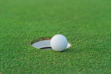 Golf ball on lip of cup at golfcourt