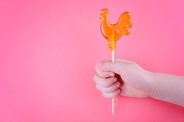 Lollipop cock in the hand of a child. On pink background