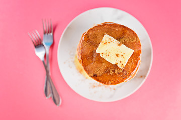 High pile of pancakes with butter, honey, cinnamon on top.
