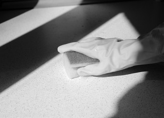Hand in rubber glove washing surface on a sunny day. Spring cleaning black and white