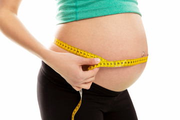 A pregnant woman measures the abdominal circumference. Late term of pregnancy. Close-up. Isolated on a white background.