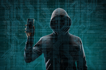 Dangerous hacker with a smartphone gadget over digital background with binary code. Obscured dark face in mask and hood. Data thief, internet attack, darknet fraud, virtual reality and cyber security.