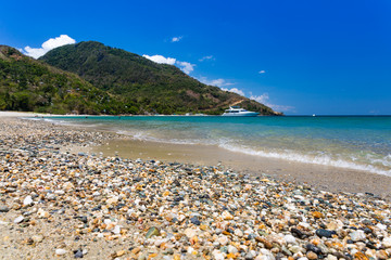 Aninuan beach, Puerto Galera, Oriental Mindoro in the Philippines, landscape view with cobbles and shells at the foreground.