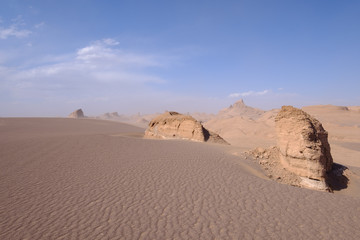 Fototapeta na wymiar Sand, rocks and blue sky in the Kalut Shahdad Desert, Kalouts, Shahdad, Iran