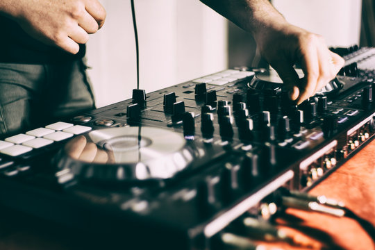 DJ playing music at mixer closeup and mixes the track in the nightclub at party