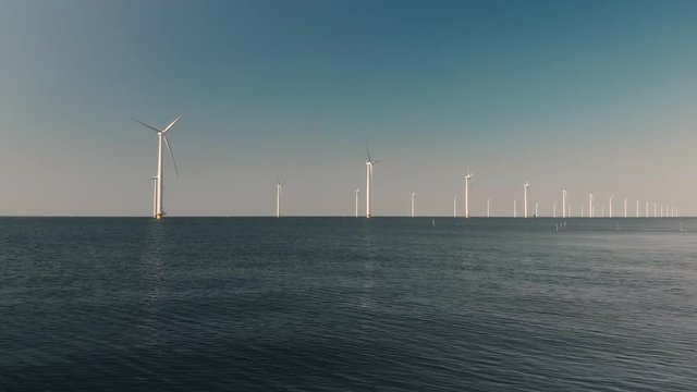 Aerial shot of Wind Farm Turbines with Swans in the Foreground, at Sea in The Netherlands, Generating Green Energy