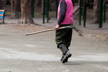 The worker is sweeping the lawn in the park.