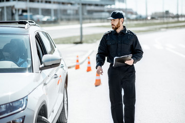 Fototapeta premium Policeman walking to the stopped car for the violation traffic rules on the city road