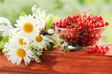 A bouquet of wildflowers and a glass bowl of red currant