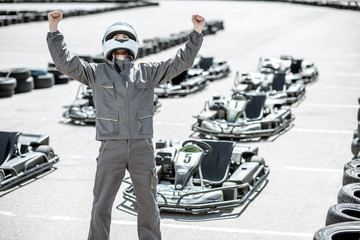 Portrait of a happy racer in protective sportswear standing as a winner of a go-kart race outdoors - obrazy, fototapety, plakaty