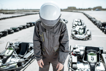 Despair racer in sportswear feeling sad standing as a loser on the go-kart track outdoors