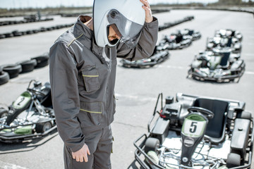 Despair racer in sportswear feeling sad standing as a loser on the go-kart track outdoors