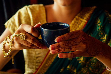 woman indian hold cup tea masala national smile.Female hands decoratively colored by henna with coffee mug - obrazy, fototapety, plakaty