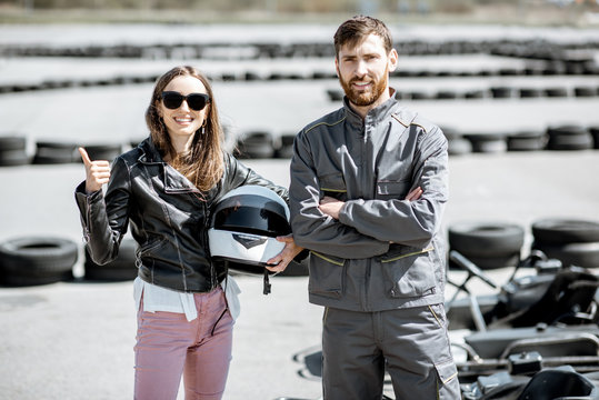 Happy instructor in sportswear with young woman driver on the go-kart track outdoors