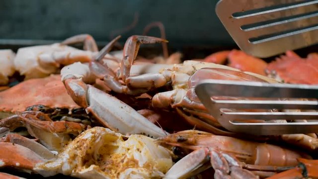 flipping group of steaming hot blue crabs and large shrimp in pile