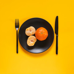Tangerines in black plate on yellow