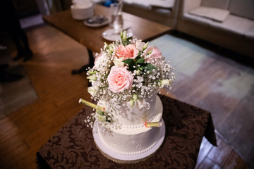 Wedding cake decorated with flowers on the table in a restaurant