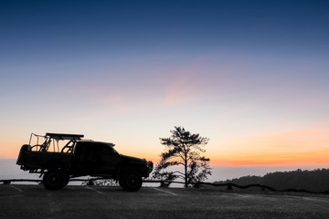 Fototapeta premium Mountain view evening, silhouette of a 4WD. Truck parking on top hill with colorful vivid sky background, sunset at Huai Nam Dang National Park, Chiang Mai, northern of Thailand.