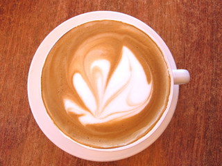 Flat White Coffee in white cup on timber cafe table