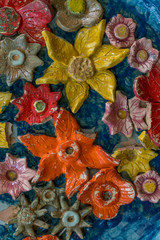 Obraz na płótnie Canvas Colorful ceramic flowers some with broken petals on a blue background image with copy space