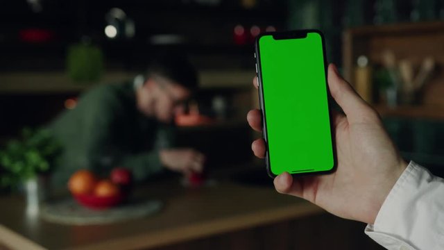 Slow motion hands hold use smartphone with vertical green screen on kitchen at home background man drink tea sad breakfast apple fruit browse house internet finger payment communication close up