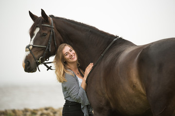 Reiterin lehnt sich an ihr Pferd im Portrait am Deich