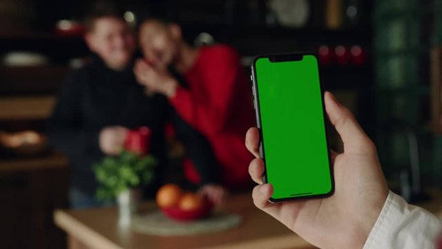 Shot hands hold use smartphone with vertical green screen on kitchen at home background gay couple happy quarrel breakfast apple fruit browse house internet finger payment communication close up