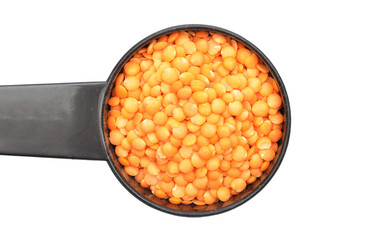 Rote Linsen auf Dosierlöffel und weißem Hintergrund