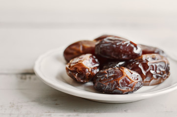 Small plate with sweet dried dates on wooden table. Healthy snack