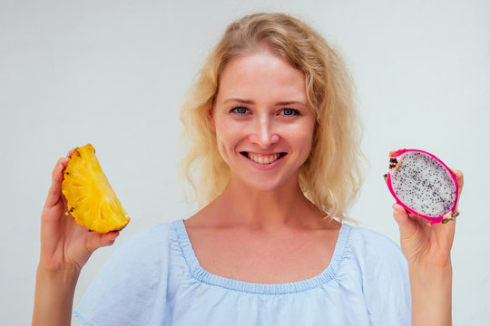 Portrait Of Beautiful Blond Hair Woman With Blue Eyes Holding Pineapple And Dragon Fruit On White Background.detox And Allergy To Tropical Products