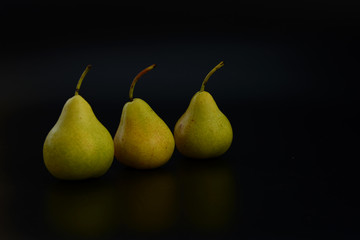 Three green pears on a black background. The insulation on the black. Green pear fruit.Healthy and healthy food. fruits.