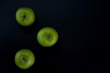 Three green apples on a black background. The insulation on the black. Fruits green apples.Healthy and healthy food. fruits.