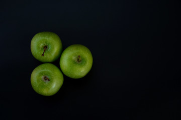 Three green apples on a black background. The insulation on the black. Fruits green apples.Healthy and healthy food. fruits.