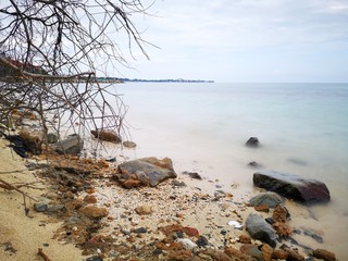 The beautiful silky smooth water waves and rocks on the sea shore.